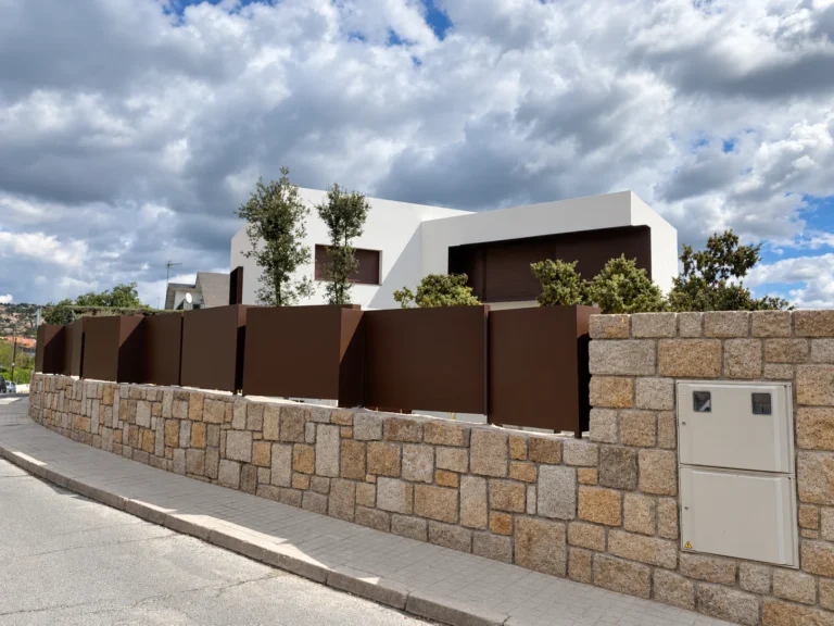 Vivienda unifamiliar con fachada blanca y cerramiento de piedra en Torrelodones
